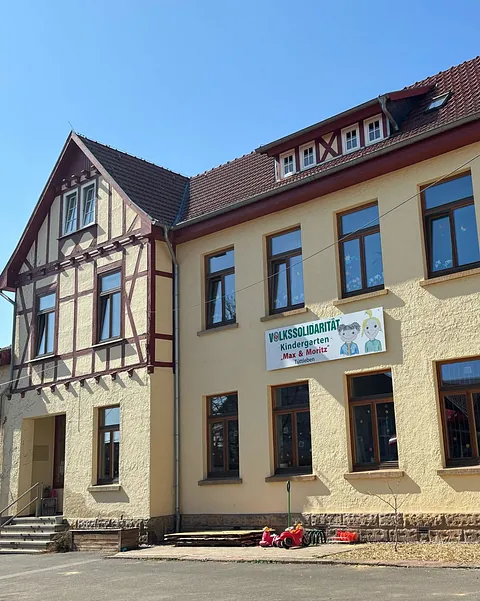Gelbes Haus mit braunem Dach und einem Banner vorne